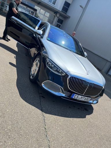 Schwarzer Luxuswagen mit offenem Fahrerbereich auf einer Asphaltoberfläche.