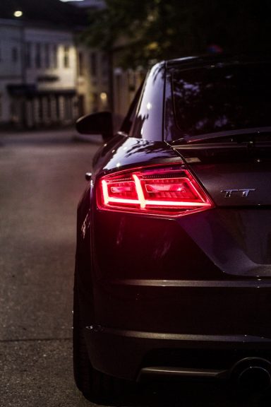 Heckansicht eines Autos mit leuchtenden Rücklichtern in einer nächtlichen Straße.