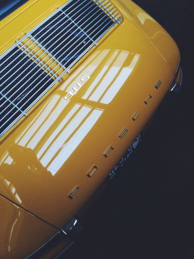 Gelber Porsche mit glänzender Karosserie und sichtbarem Schriftzug.