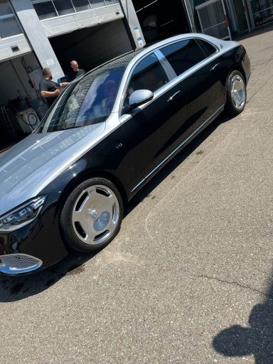 Schwarze Limousine mit silbernem Dach, sportliche Felgen, parkt draußen.
