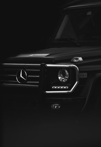 Schwarzer Mercedes G-Klasse mit markanter Frontpartie im Dunkeln.