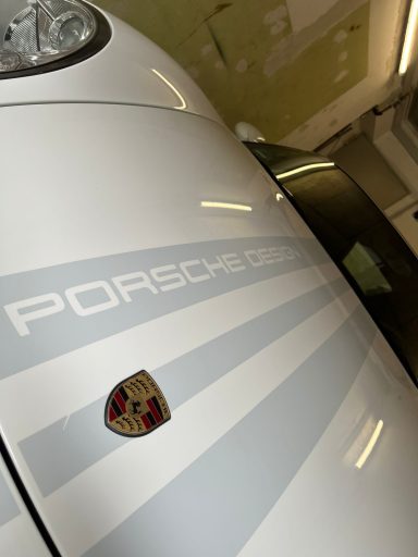 Weißer Porsche mit markantem Logo und gestreiftem Design.