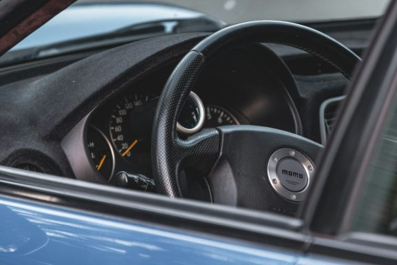 Innenansicht eines Autos mit Lenkrad und Armaturenbrett.