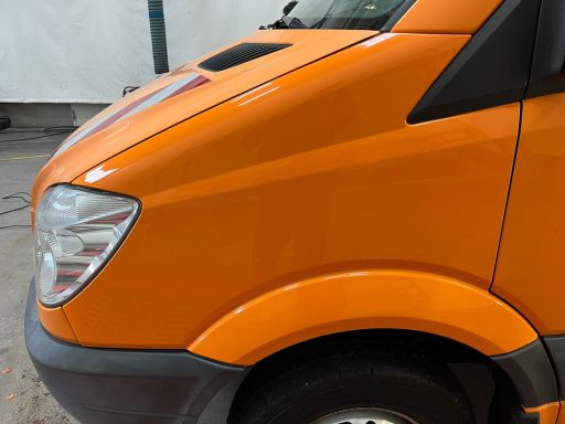 Orange Transporter von der Seite, mit geschwungenen Linien und einem flachen Dach.