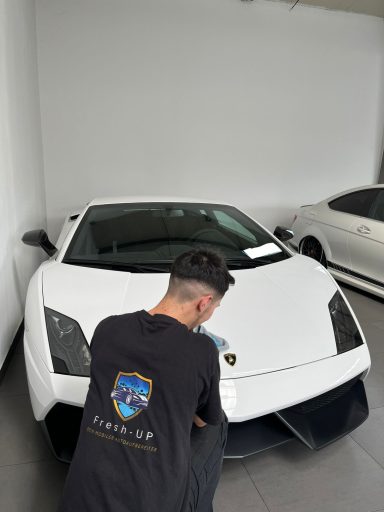 Ein Mann putzt einen weißen Sportwagen in einer modernen Garage.